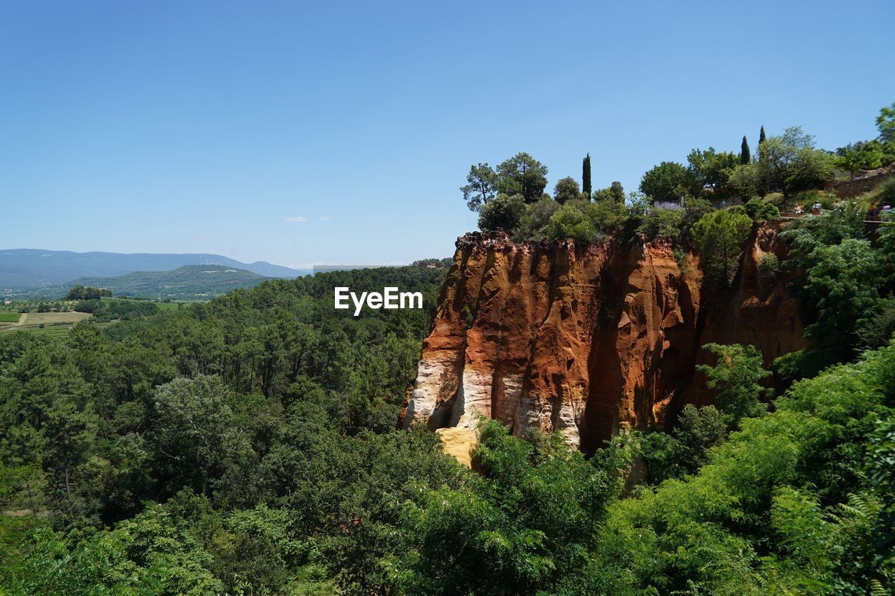 Ocher rock formations on landscape against clear blue sky