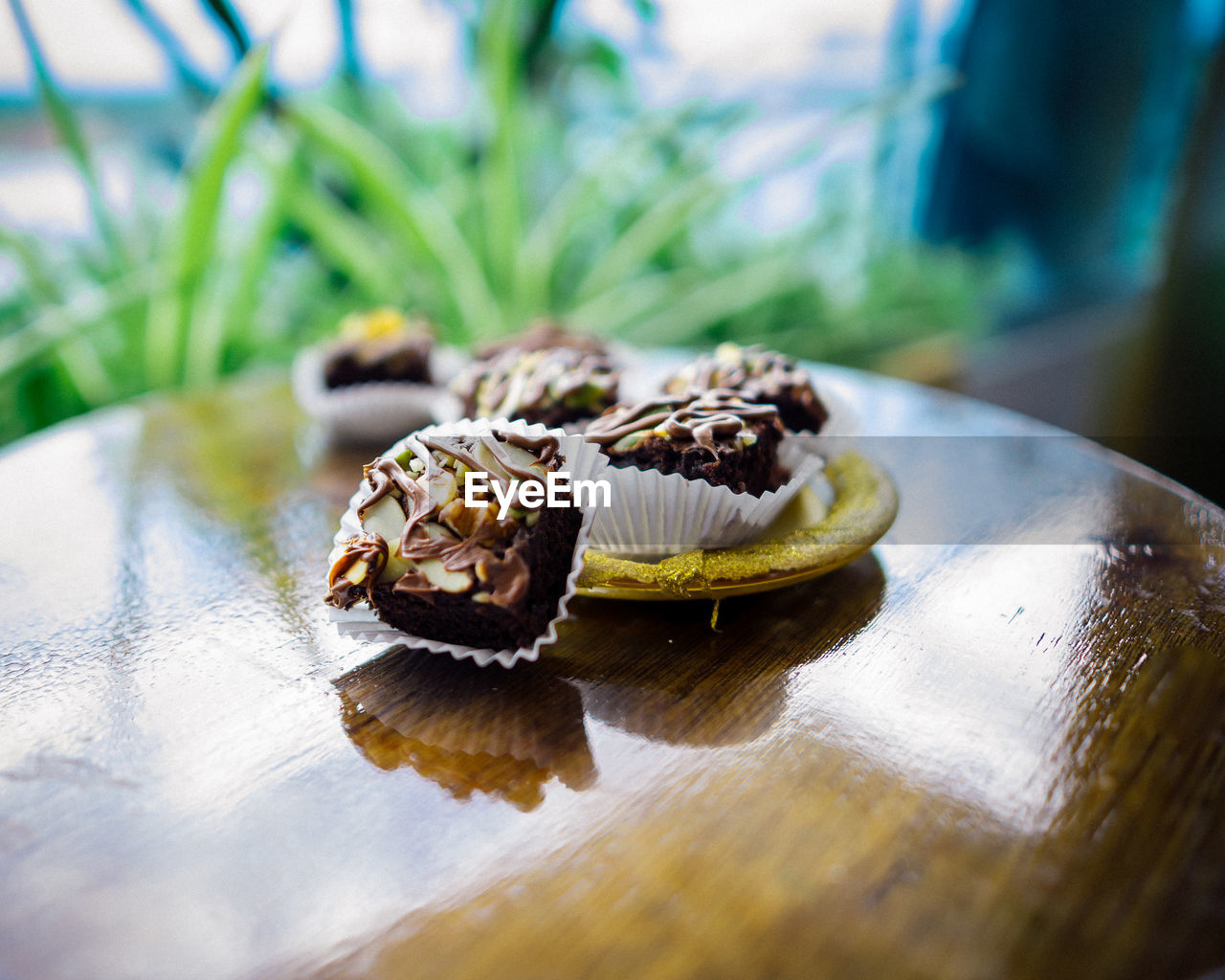 Chocolate brownie cubes with chocolate drizzle in paper cups on a wooden background.