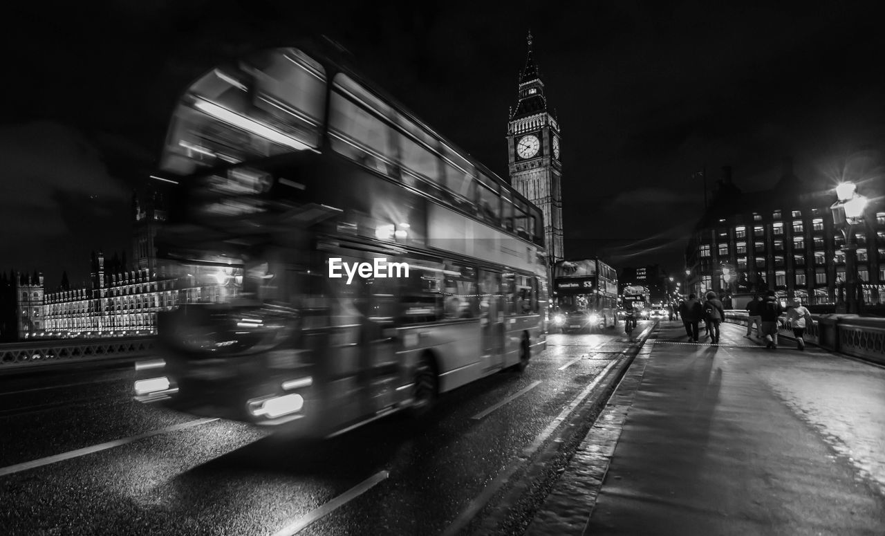 Blurred motion of double-decker bus on westminster bridge in city at night