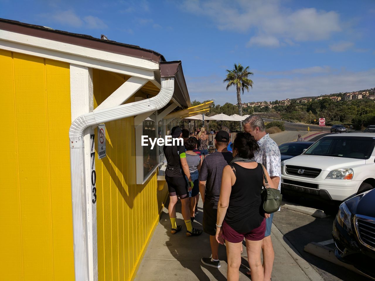 REAR VIEW OF PEOPLE STANDING ON YELLOW CAR AGAINST SKY