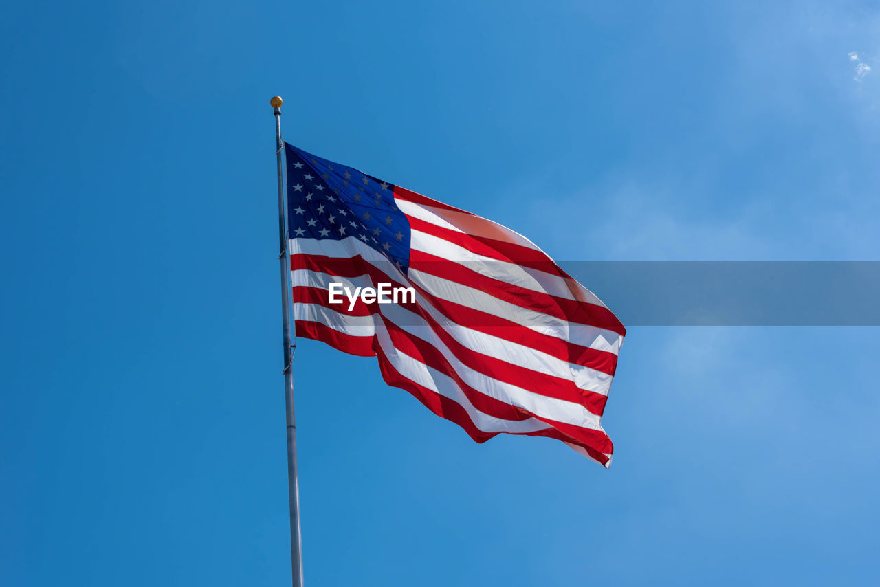 Low angle view of american flag against blue sky