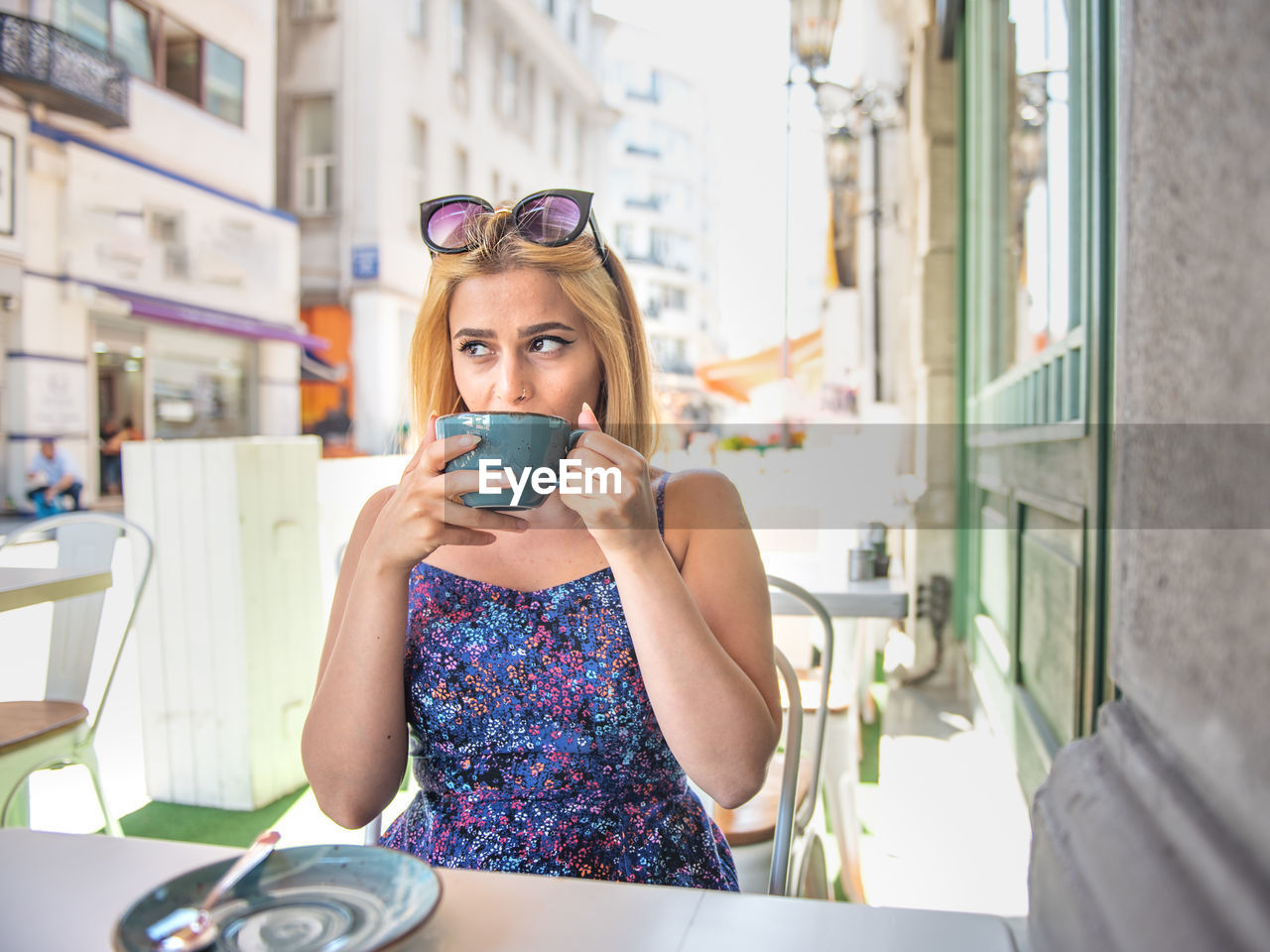 Young woman drinking coffee while sitting at cafe