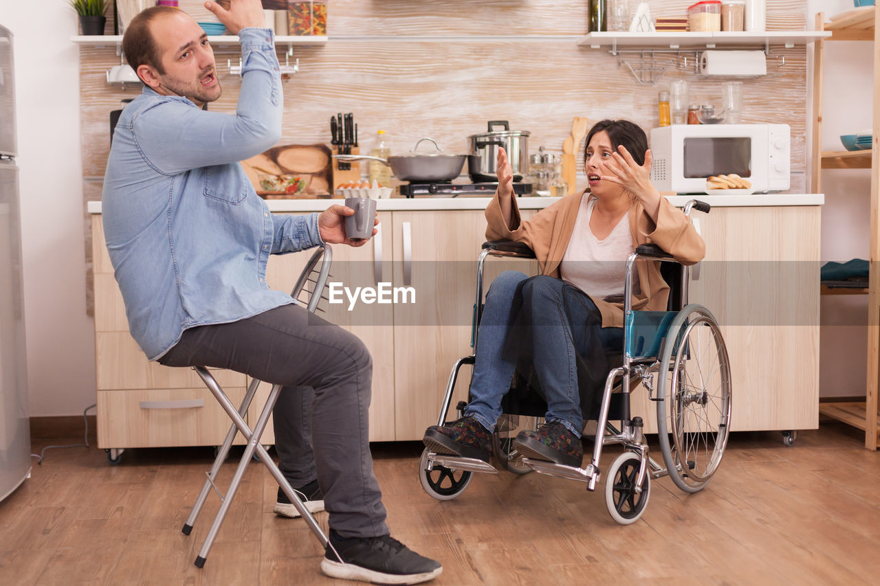 Disabled woman arguing with man in kitchen at home