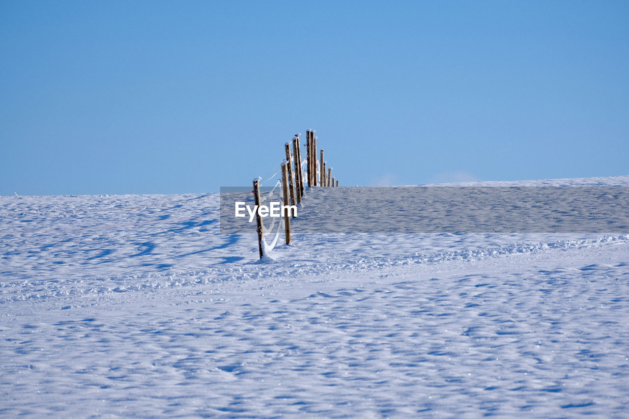 winter, snow, cold temperature, blue, nature, sky, scenics - nature, landscape, environment, day, clear sky, beauty in nature, copy space, no people, tranquility, tranquil scene, mountain, non-urban scene, land, white, sunny, outdoors, piste, travel, frozen, water, remote, sunlight