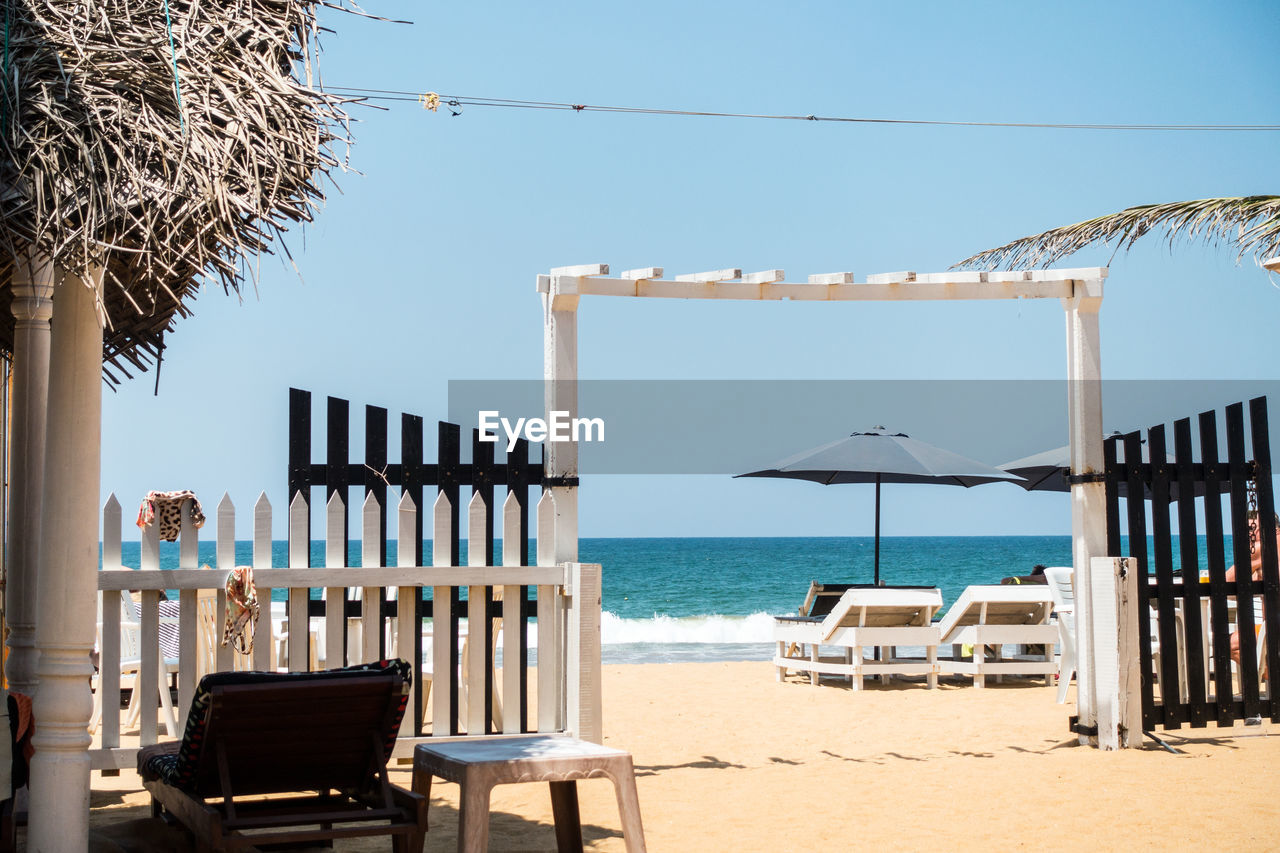 Chairs at beach against clear blue sky