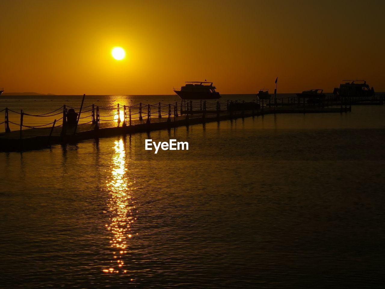 SILHOUETTE PIER ON SEA AGAINST ORANGE SKY