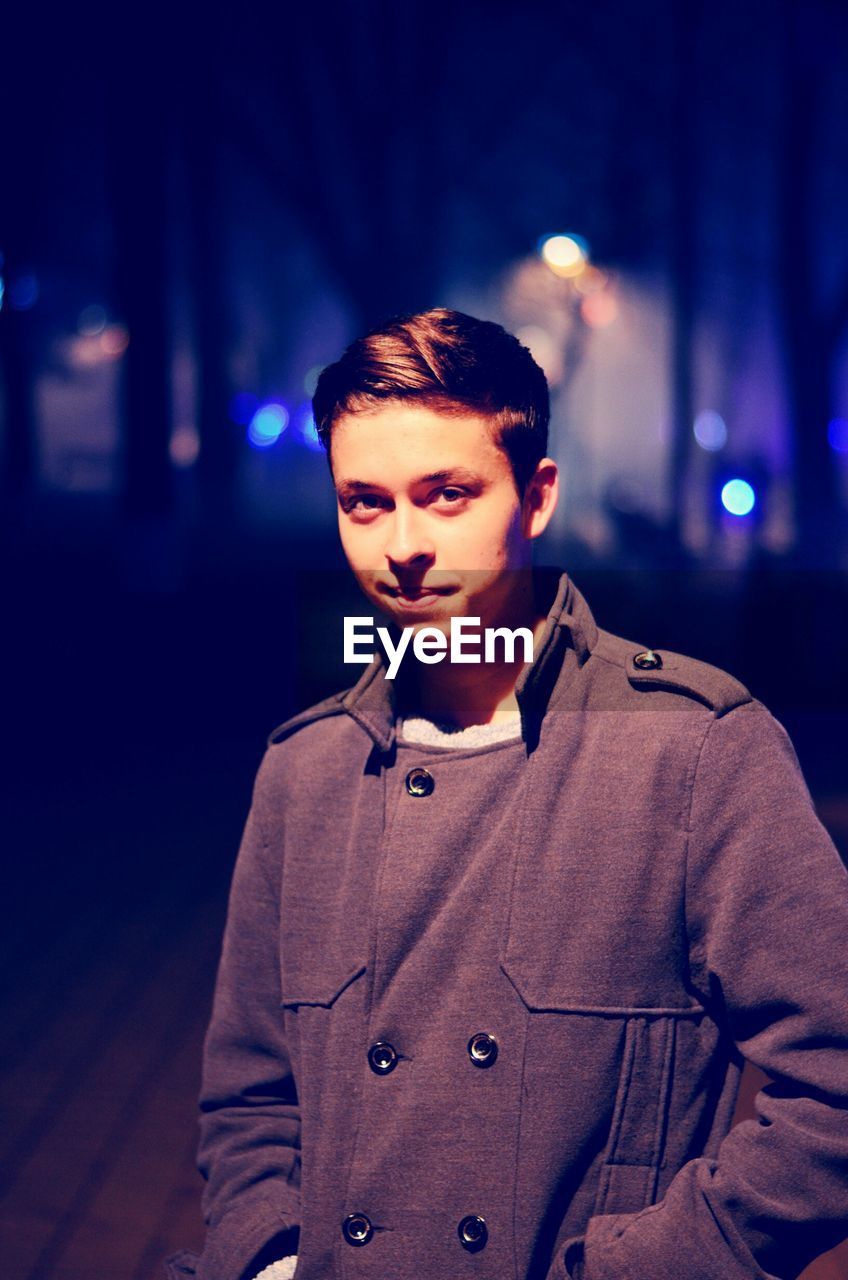 Portrait of boy standing in city at night