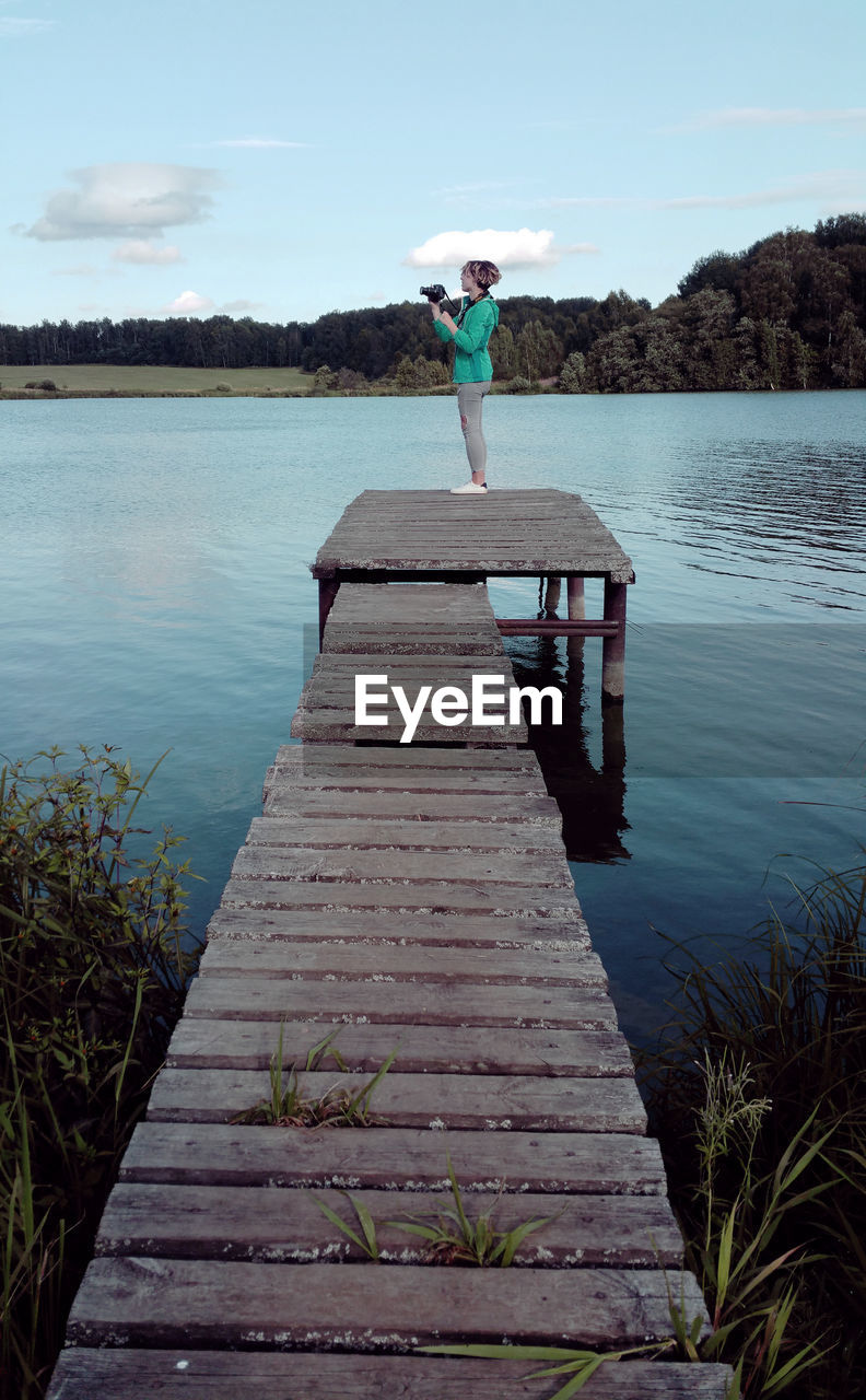 Teenage girl standing on pier at lake