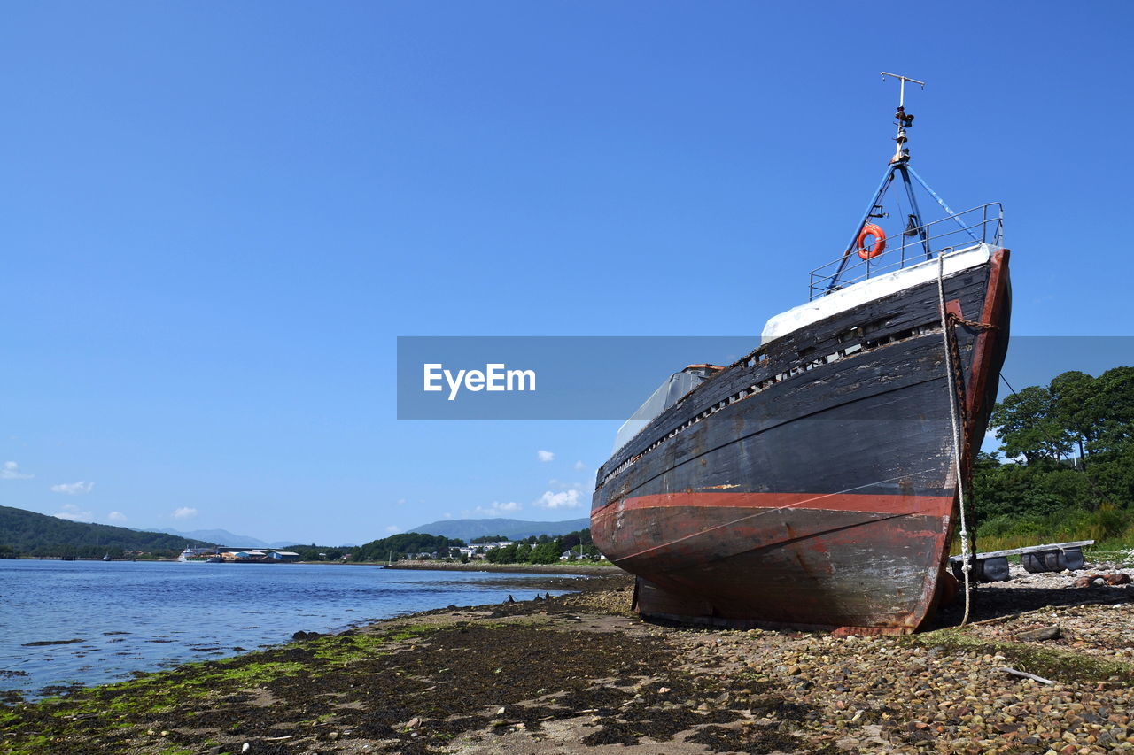 SAILBOAT MOORED ON BEACH AGAINST CLEAR SKY