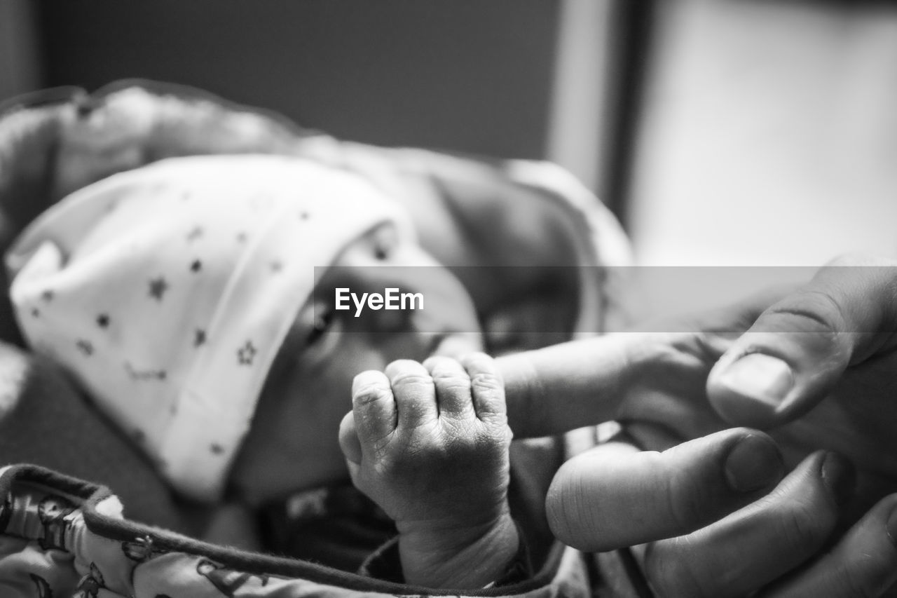 Newborn baby holding father's finger. defocused background. black and white edit.