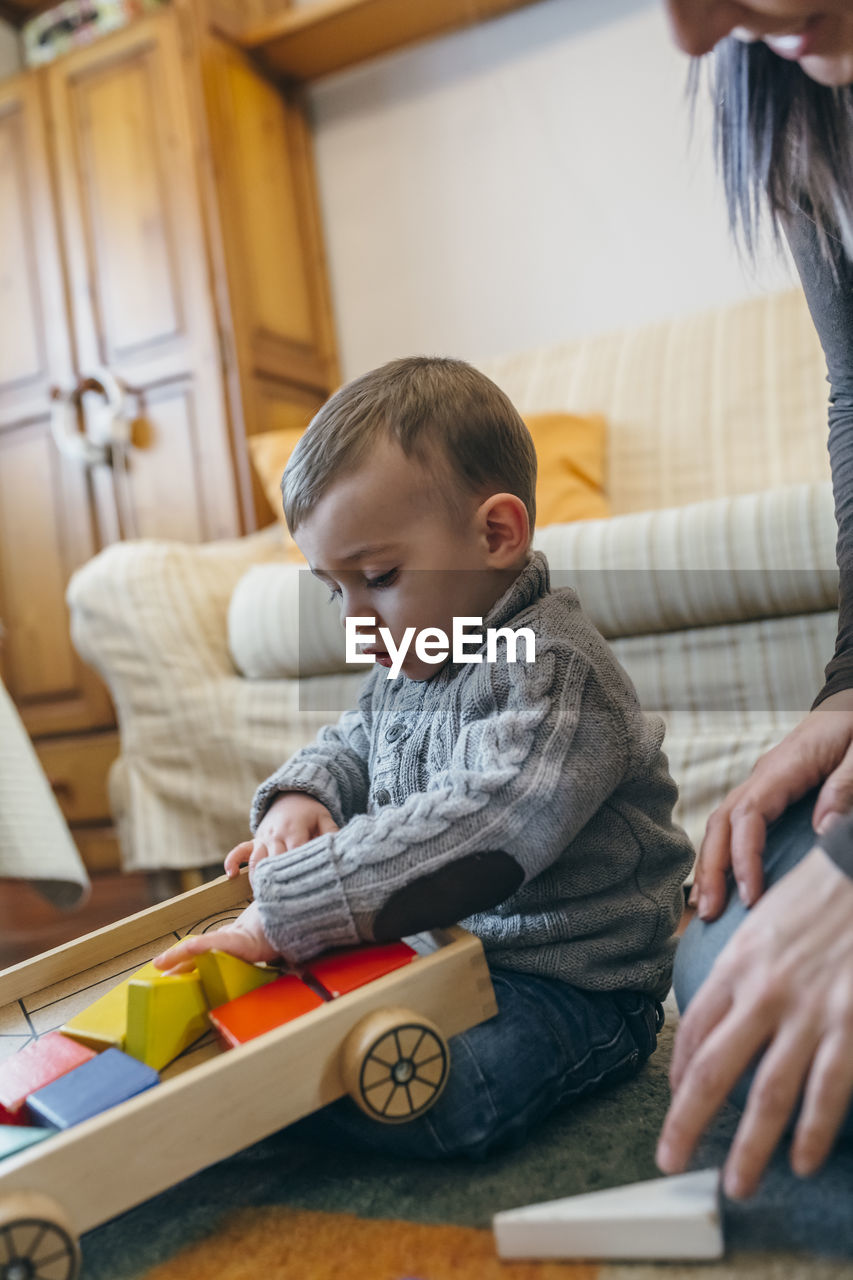 Midsection of mother playing with son while sitting at home