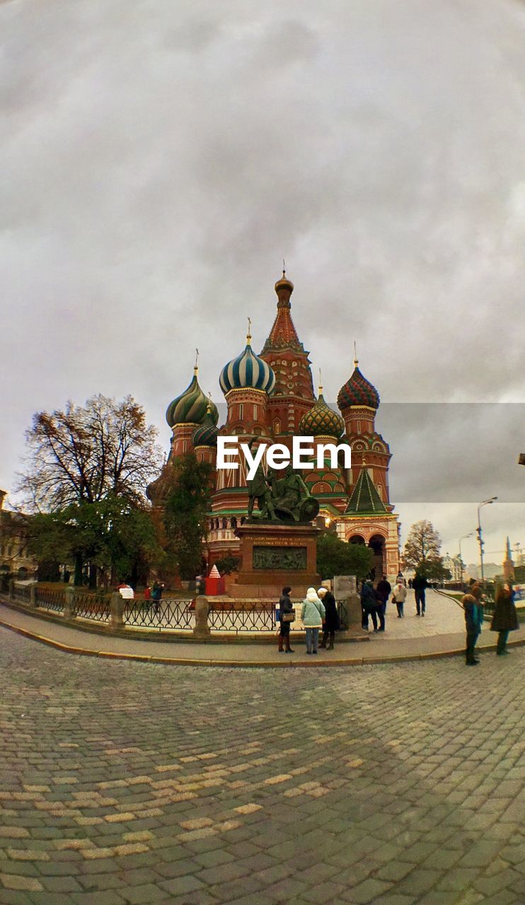 TOURISTS IN FRONT OF HISTORICAL BUILDING AGAINST CLOUDY SKY