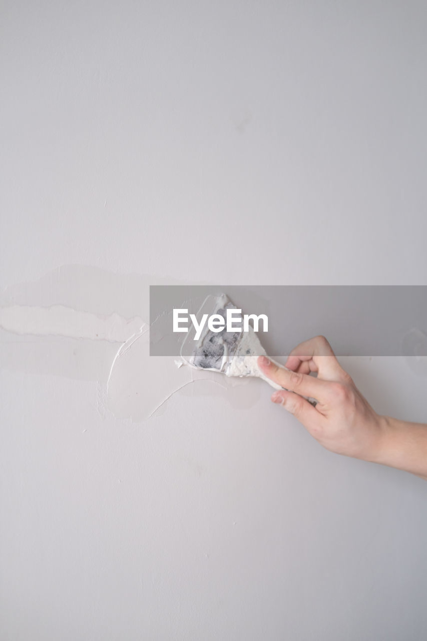 cropped hand of person cleaning brush against white background