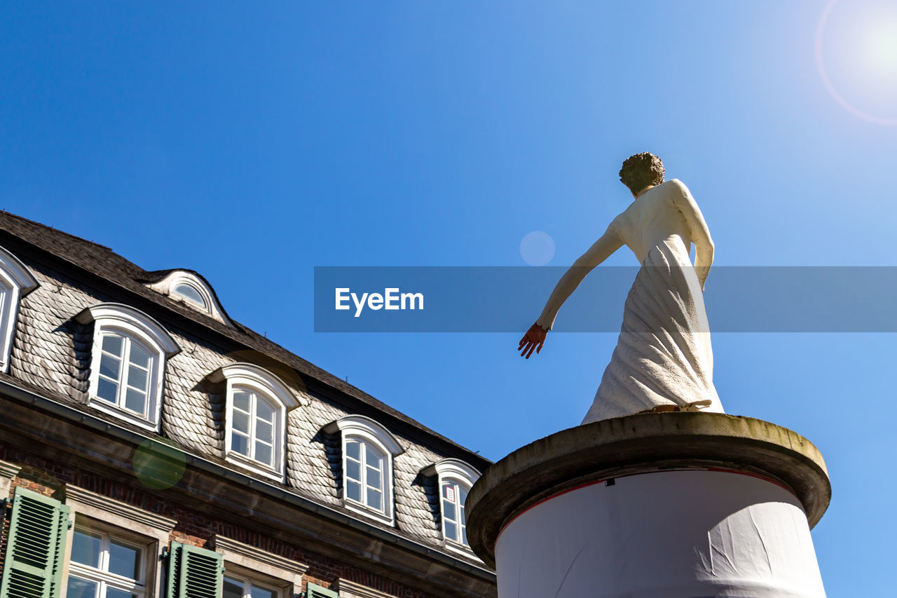 LOW ANGLE VIEW OF MAN BUILDING AGAINST CLEAR BLUE SKY