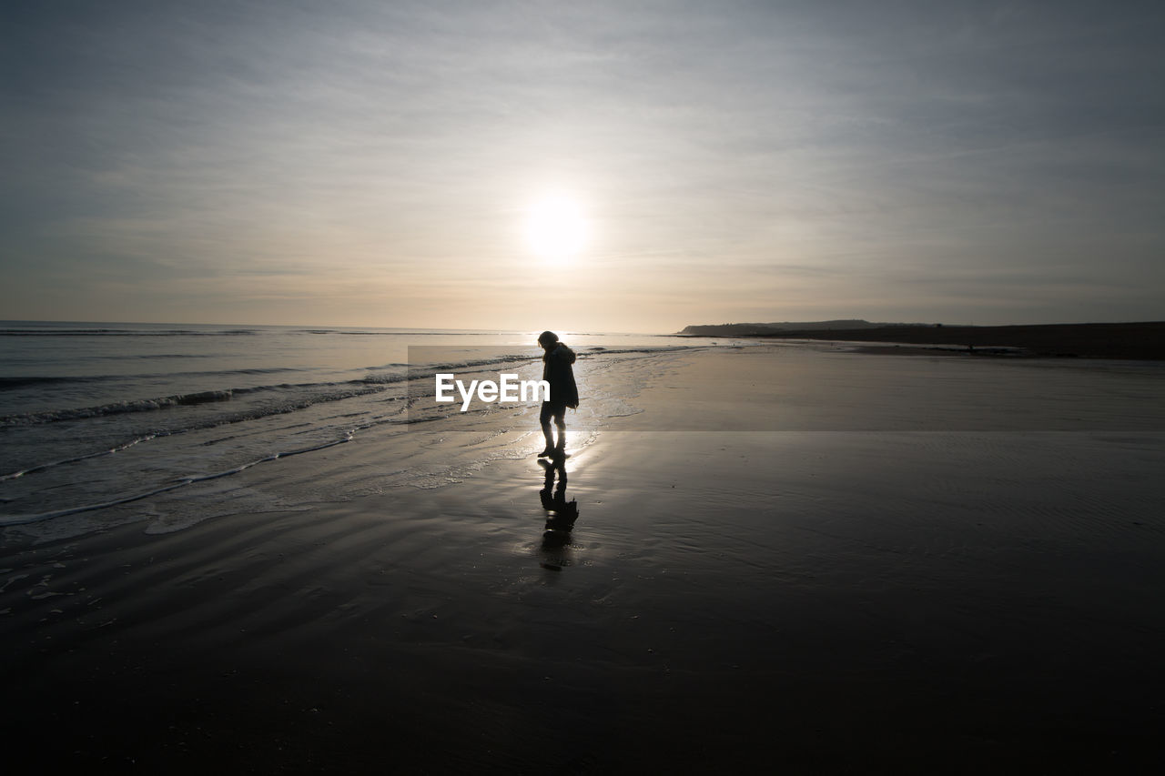 FULL LENGTH OF MAN ON BEACH AT SUNSET