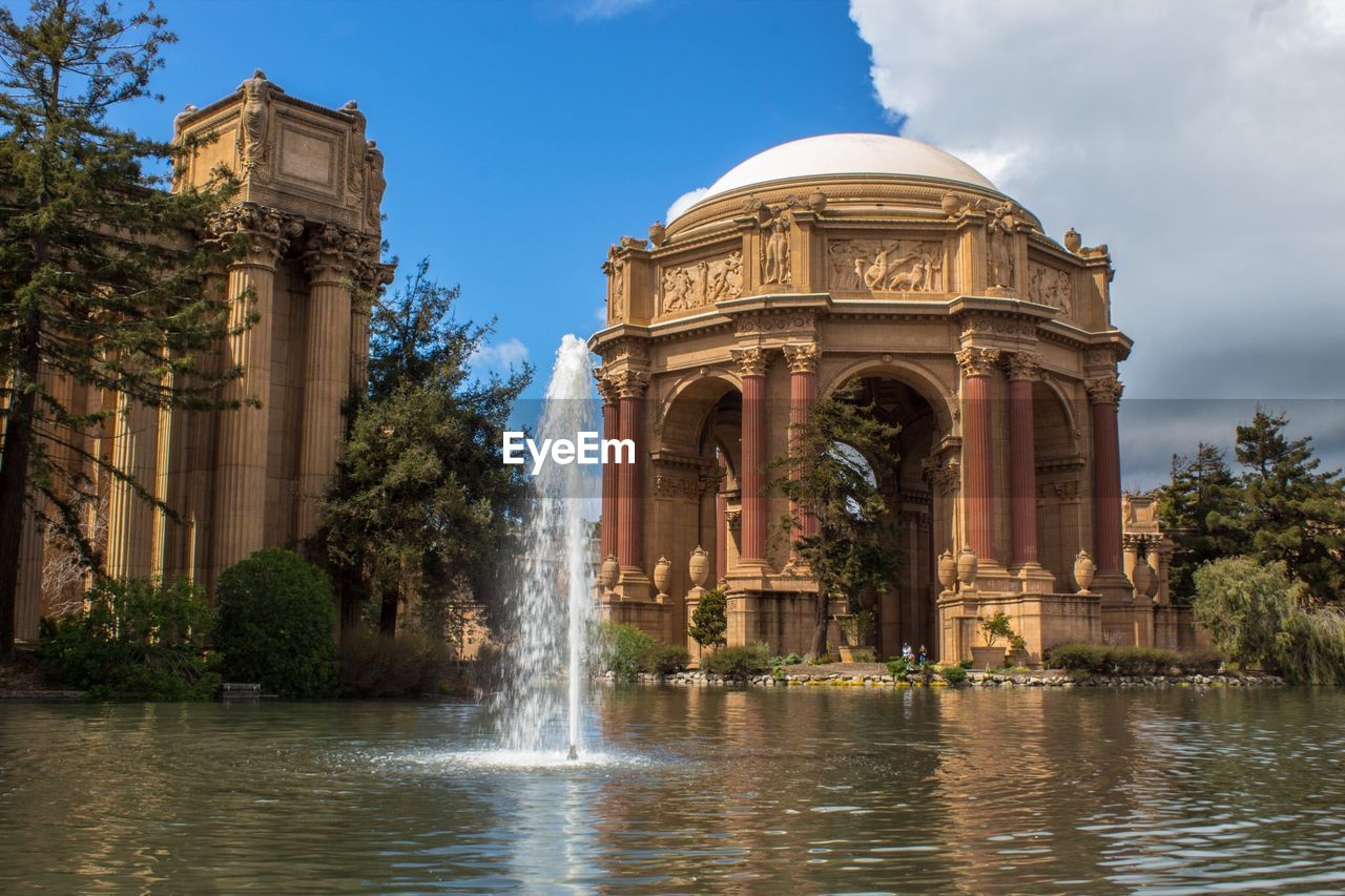 Fountain by built structure against sky