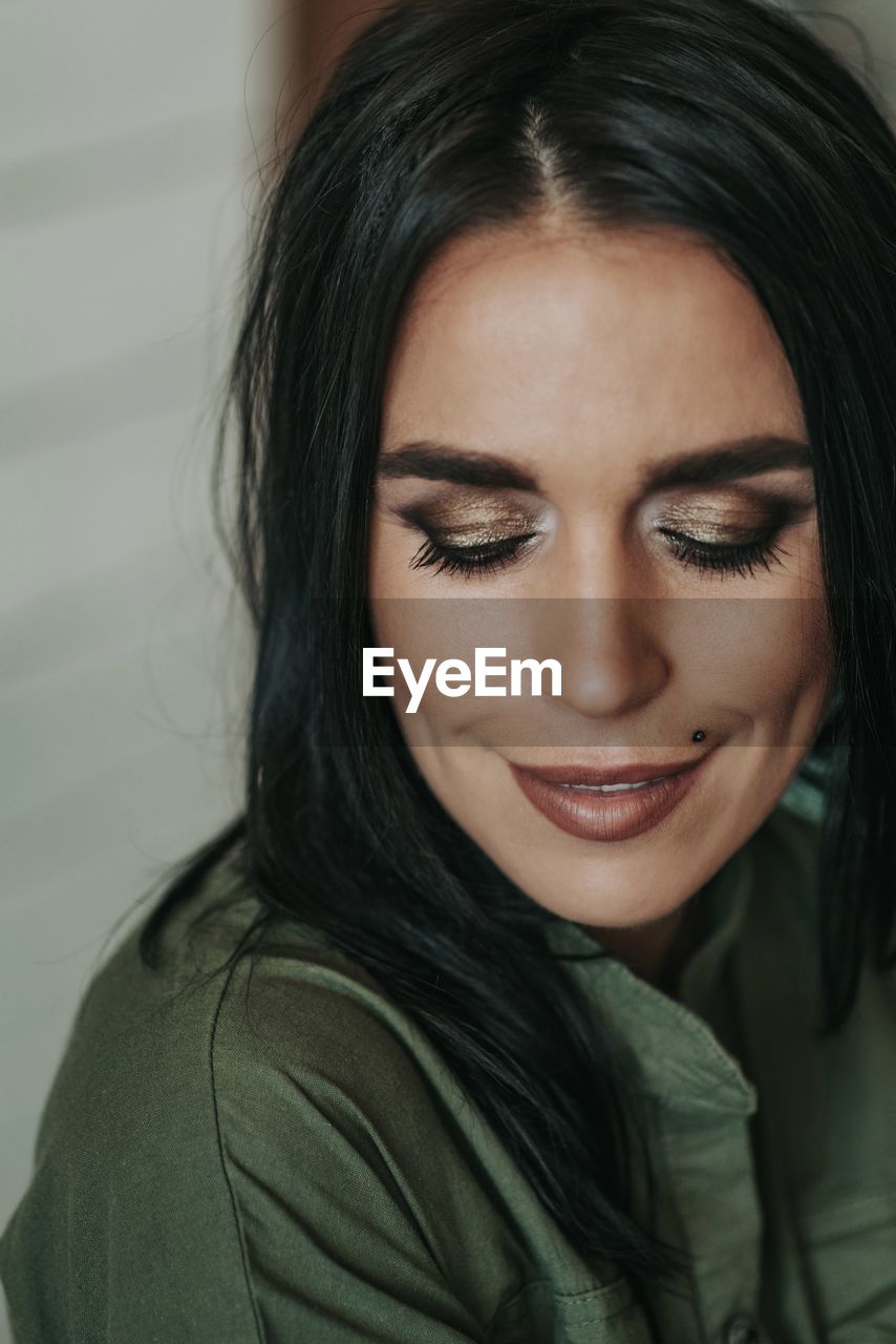 Close-up of smiling woman with make-up looking down