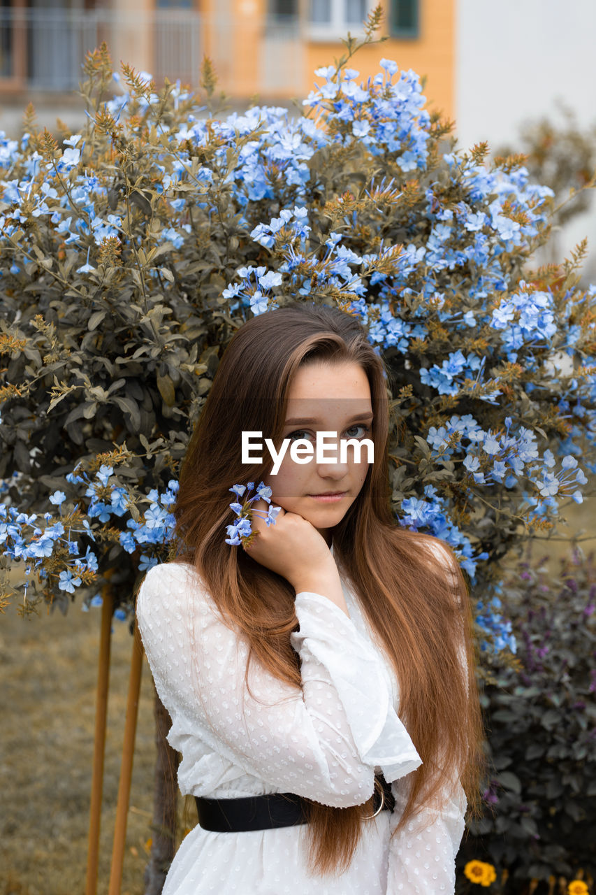 Portrait of young woman sitting against plants