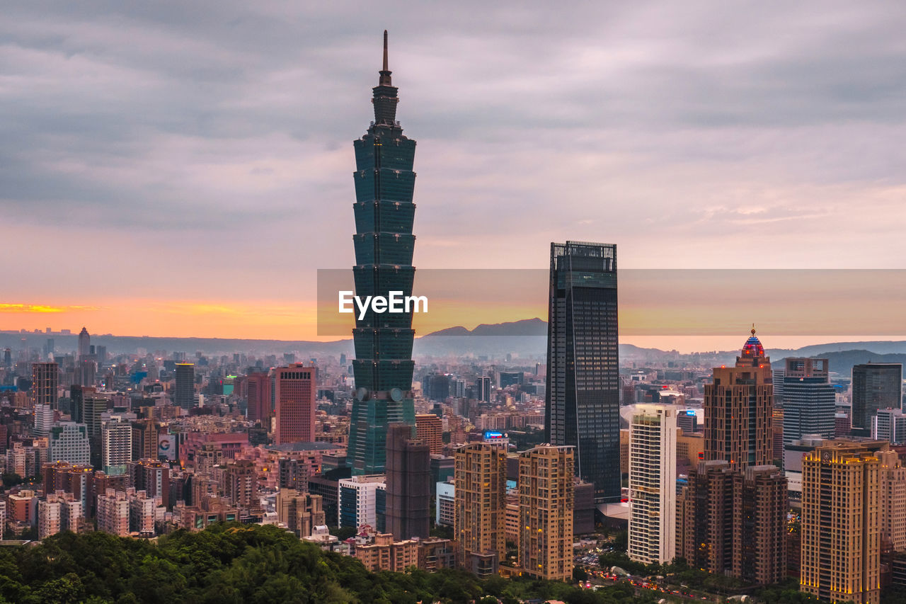 Modern buildings in city against sky during sunset