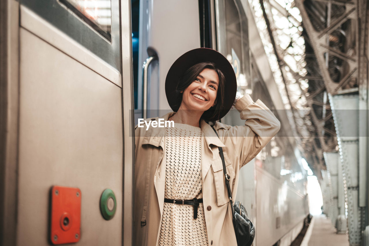 Young stylish woman traveler hanging and smiling on the train