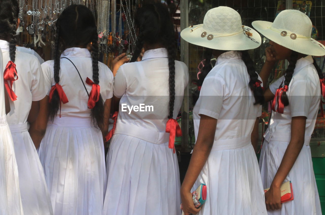 Rear view of schoolgirls shopping in market