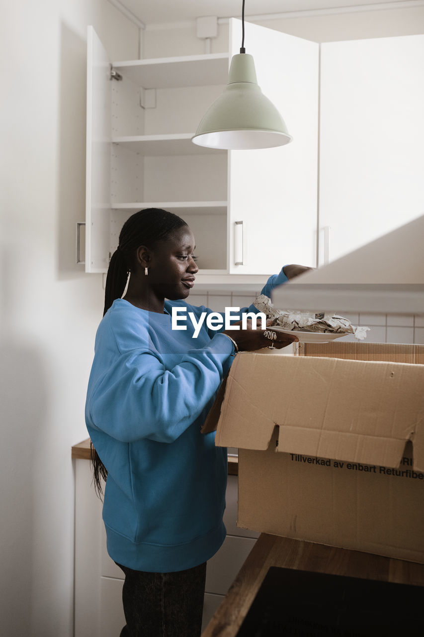 Woman unpacking box in kitchen