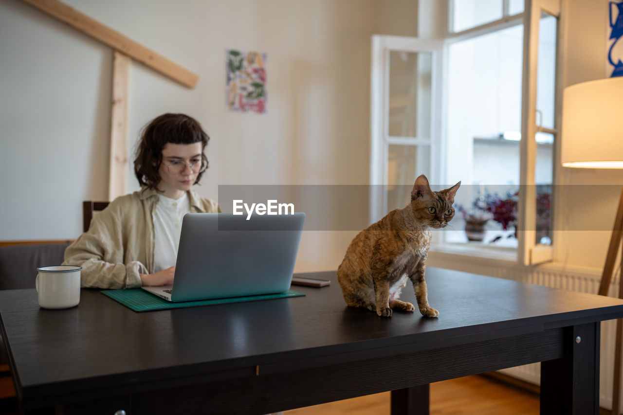 side view of woman using laptop while sitting on table