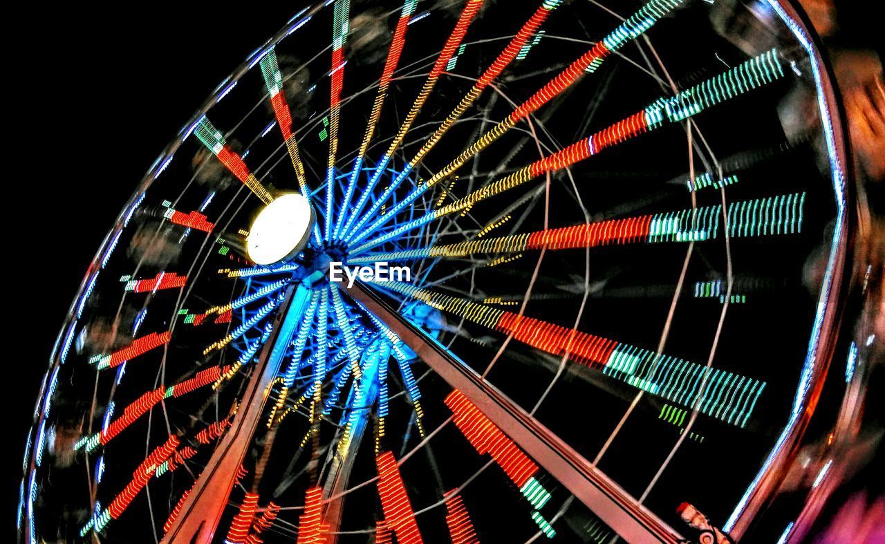 Blurred motion of illuminated ferris wheel in amusement park at night