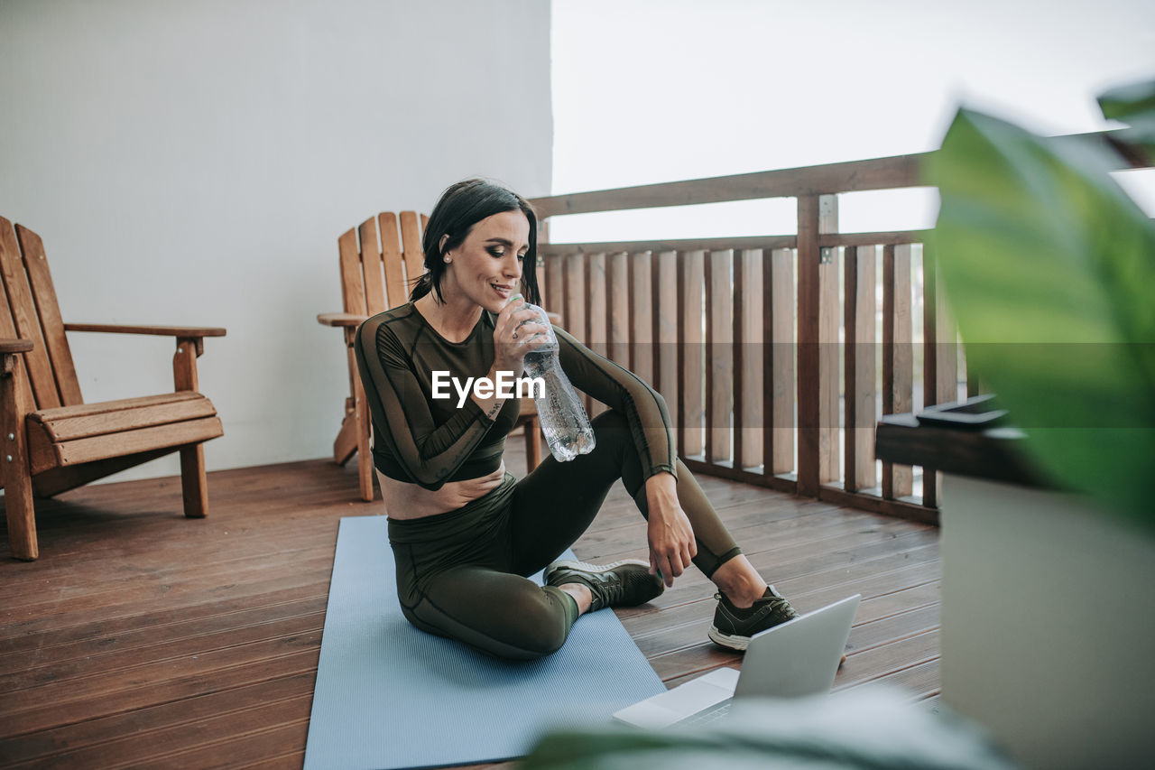 Young woman using phone while sitting on table