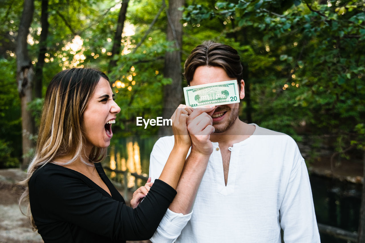 Woman holding paper currency against face of man