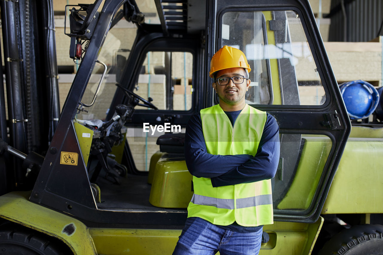 Portrait of confident worker at forklift in factory