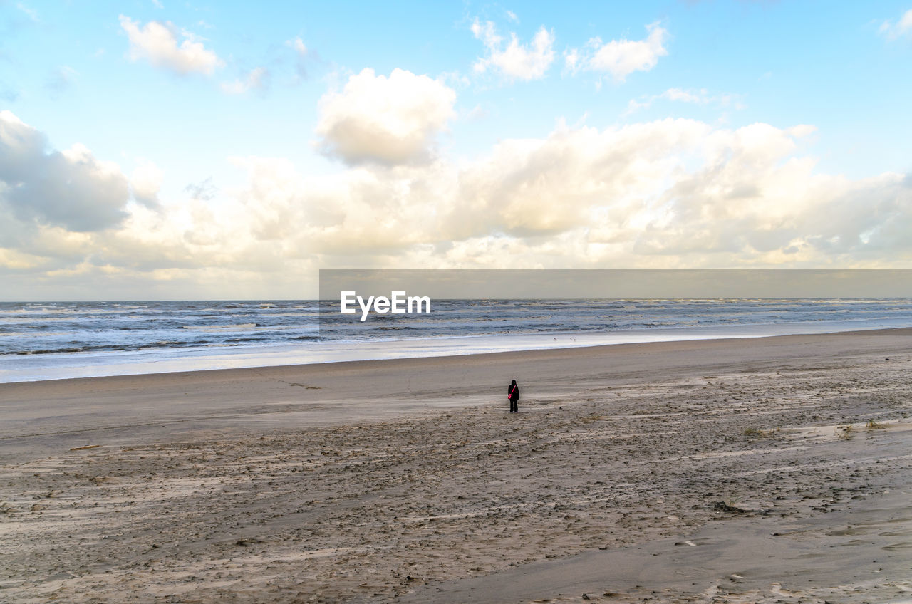 Person standing at beach against sky