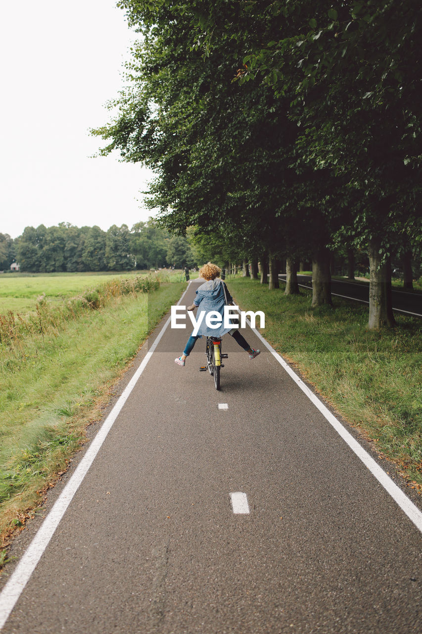 Rear view of woman riding bicycle on road