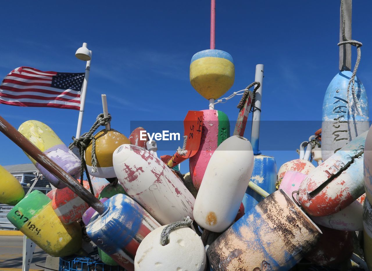 Low angle view of colorful buoys against blue sky during sunny day