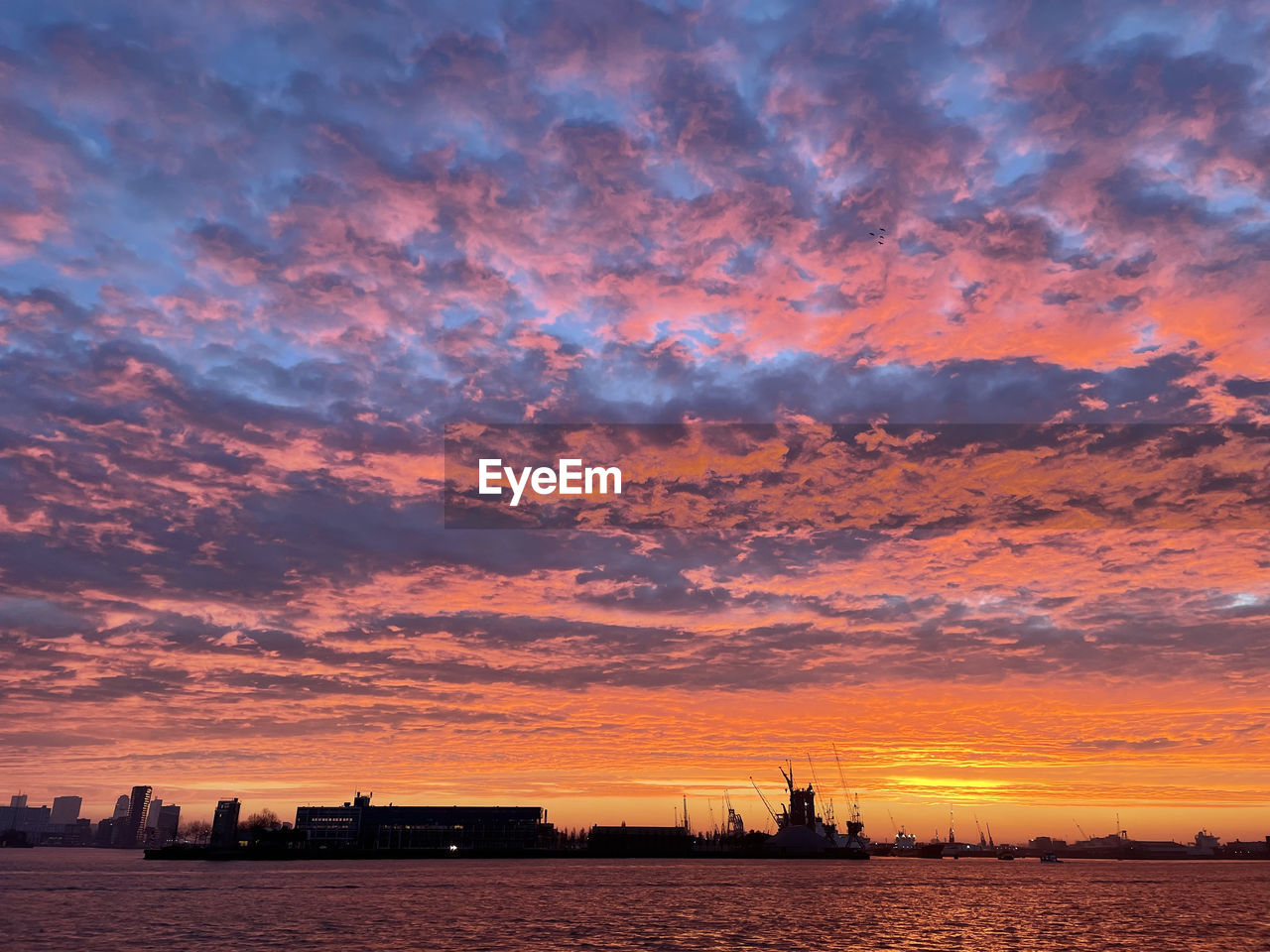 sky, afterglow, sunset, horizon, dawn, cloud, water, architecture, nature, nautical vessel, evening, transportation, sea, industry, red sky at morning, beauty in nature, environment, landscape, silhouette, business finance and industry, built structure, outdoors, dramatic sky, orange color, ship, scenics - nature, no people, harbor, city, building exterior, building, urban skyline, business, pier, mode of transportation, sun, ocean