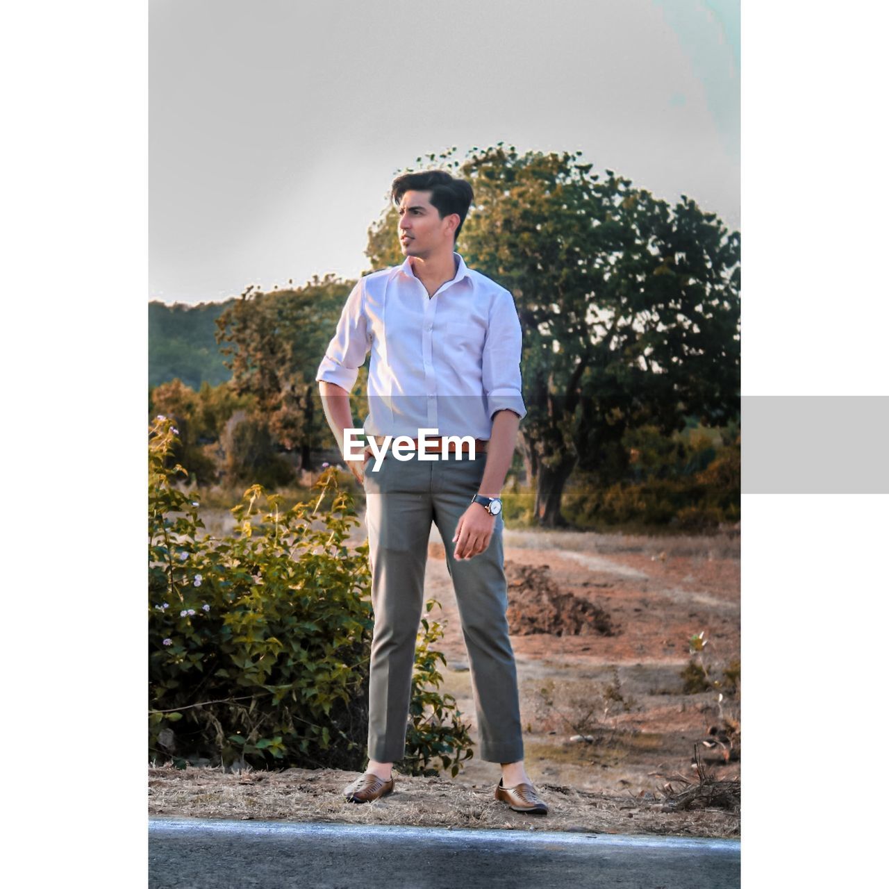 Full length of young man standing by plants against sky