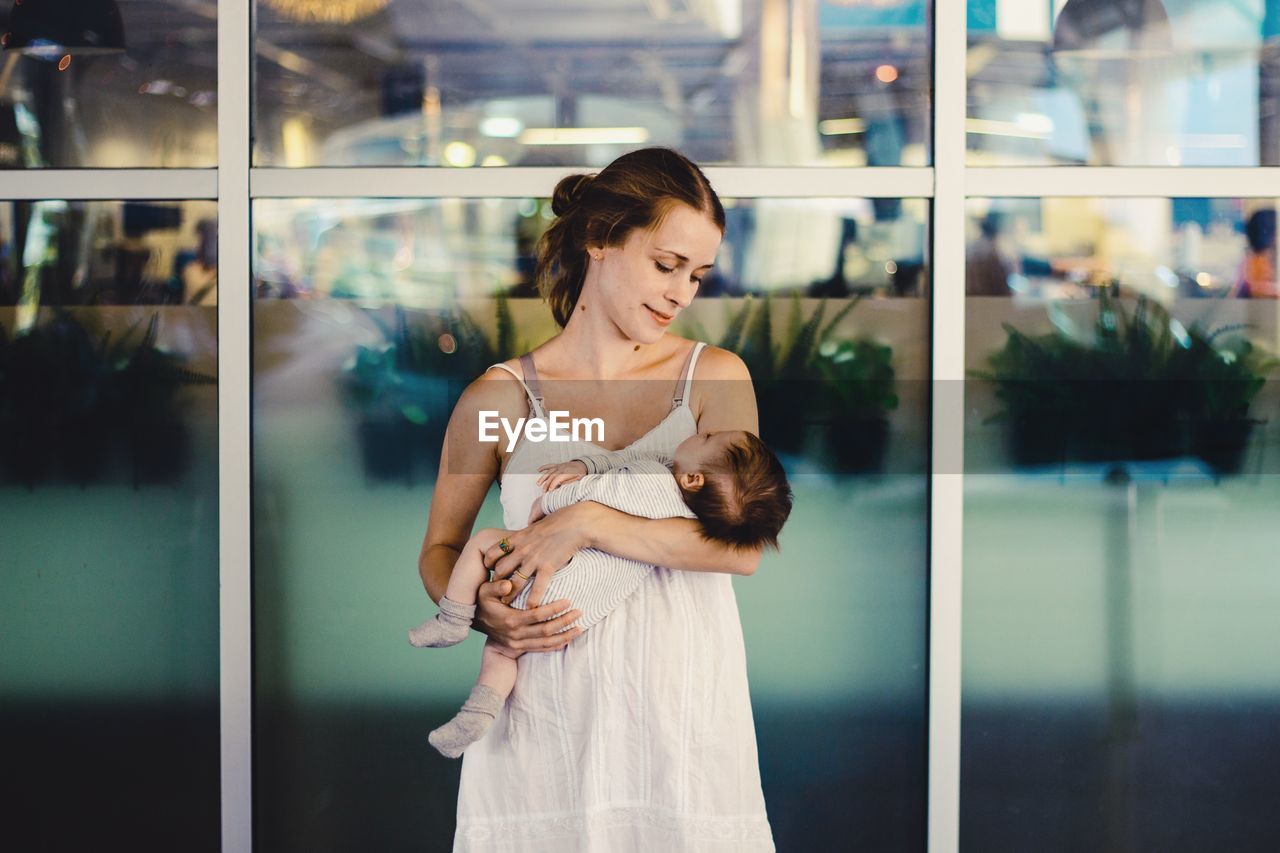 Woman holding baby against glass