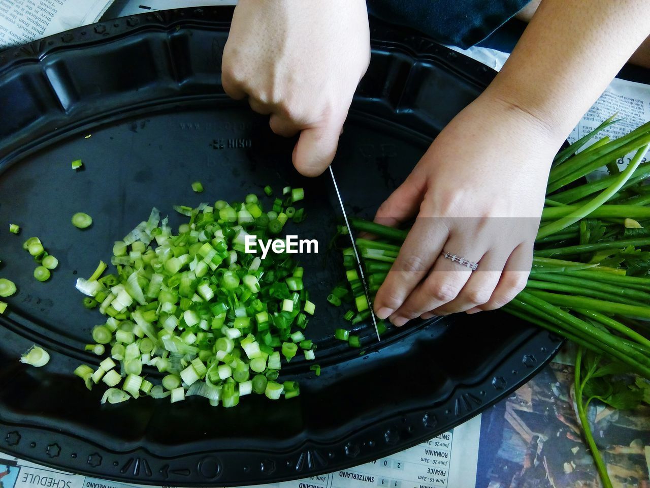 Cropped image of woman chopping spring onions in tray at home