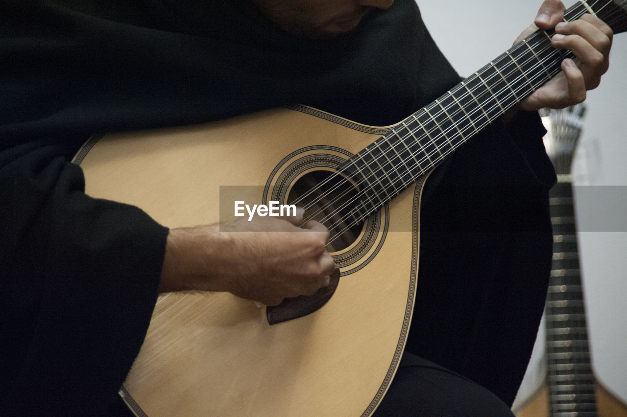 Midsection of man playing acoustic guitar