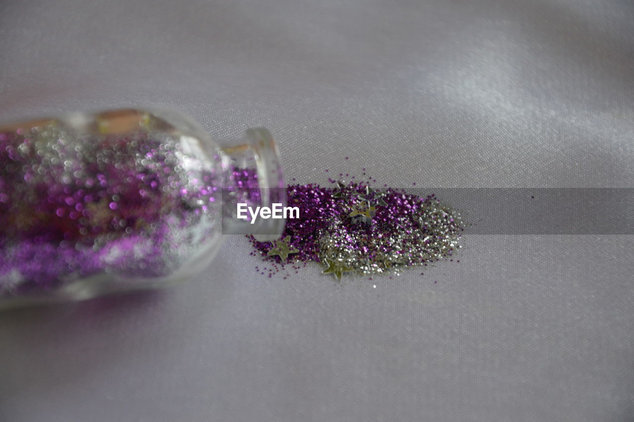 Close-up of glitter with bottle on paper