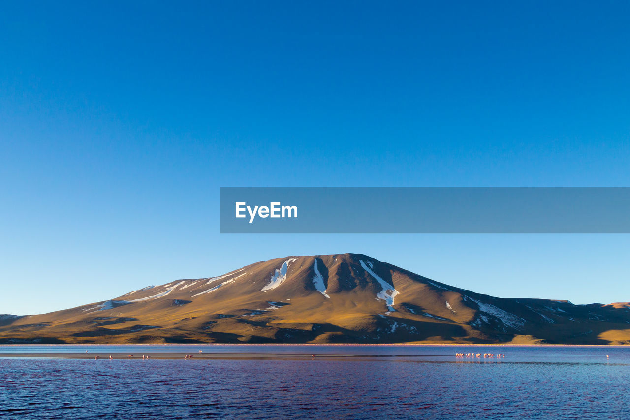 scenic view of sea and mountains against clear blue sky