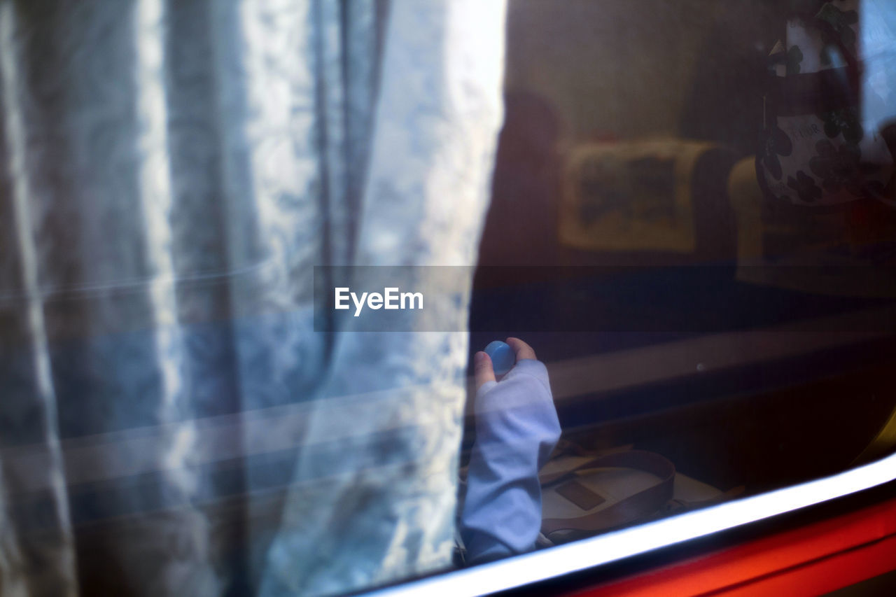 Cropped image of hand seen through train window