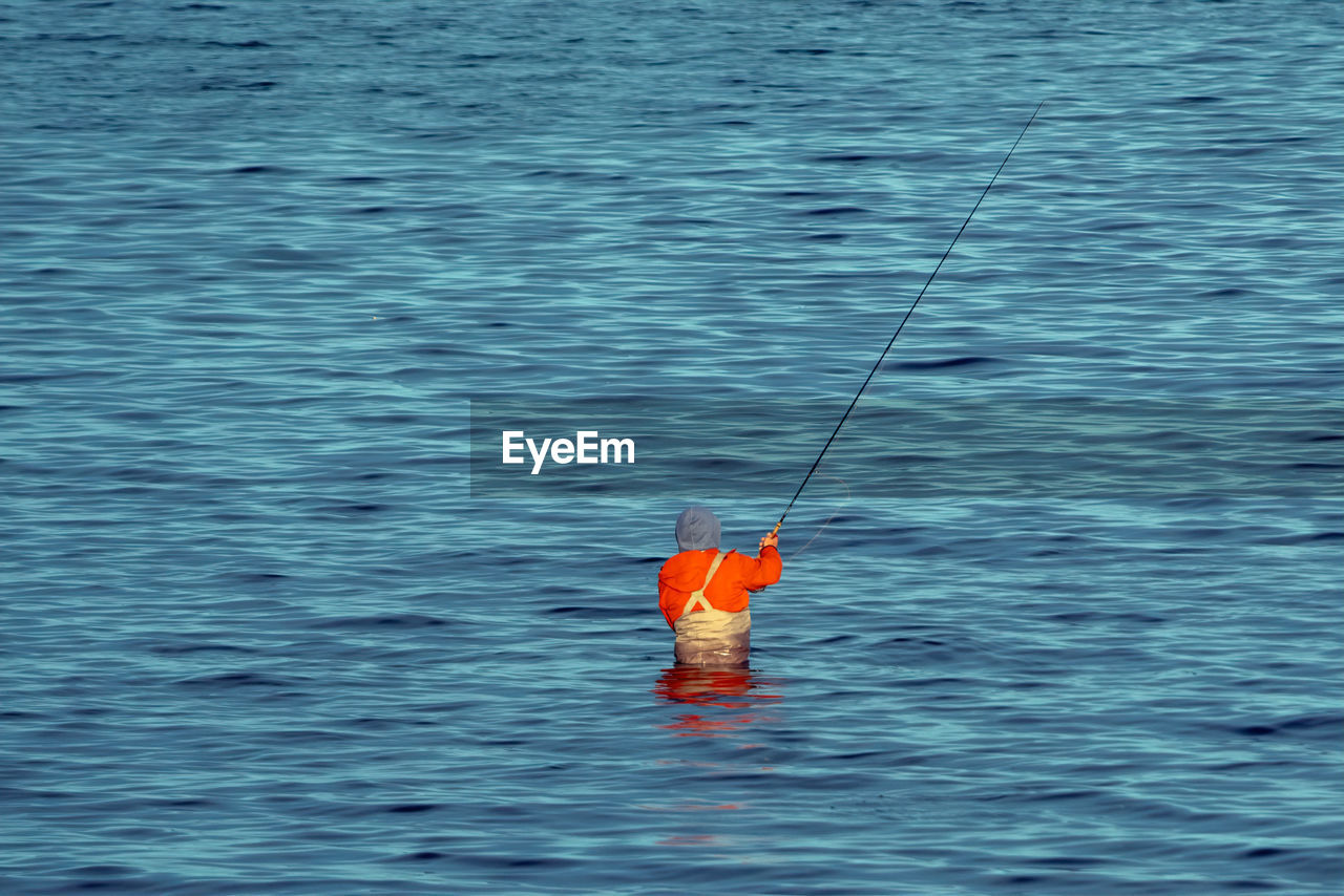 MAN HOLDING FISHING ROD IN SEA