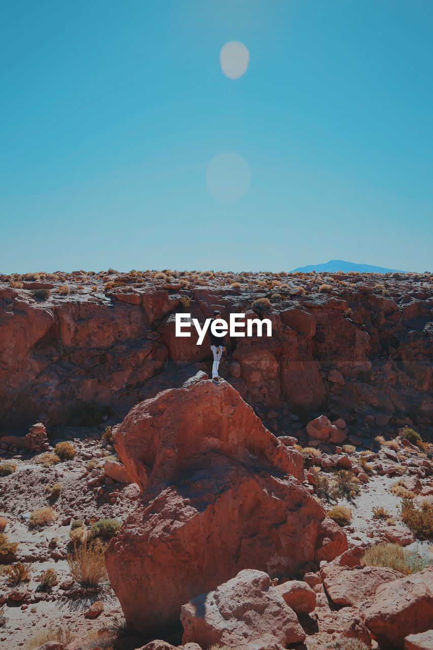 Man standing on rock against sky