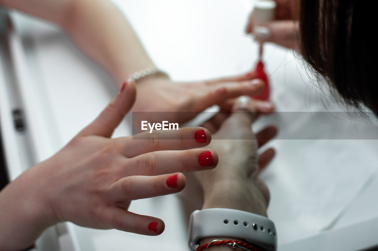 Close-up of beautician applying nail polish on hands