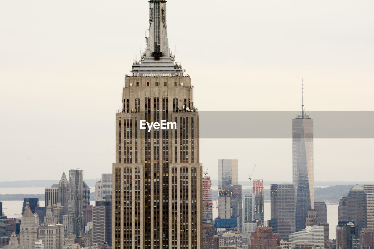 Empire state building against modern buildings at manhattan