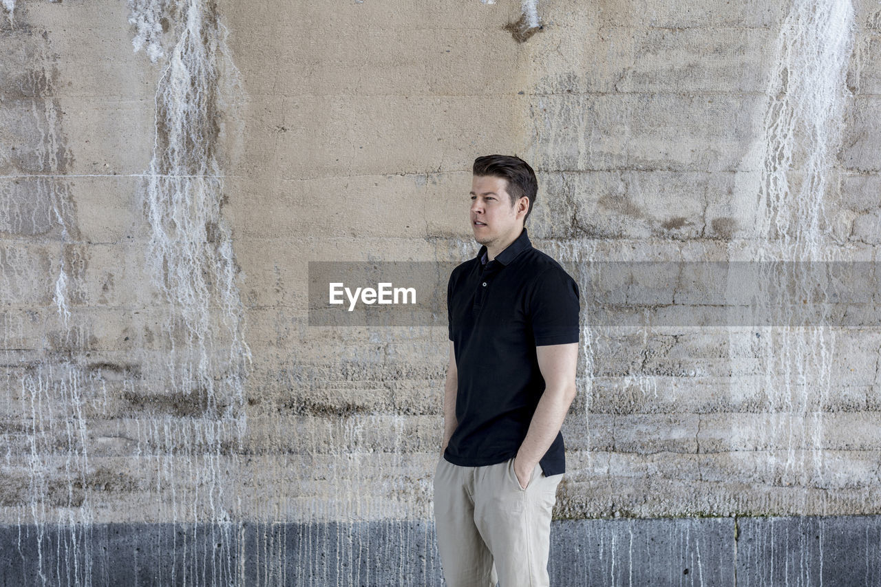 Portrait of mature man standing by wall