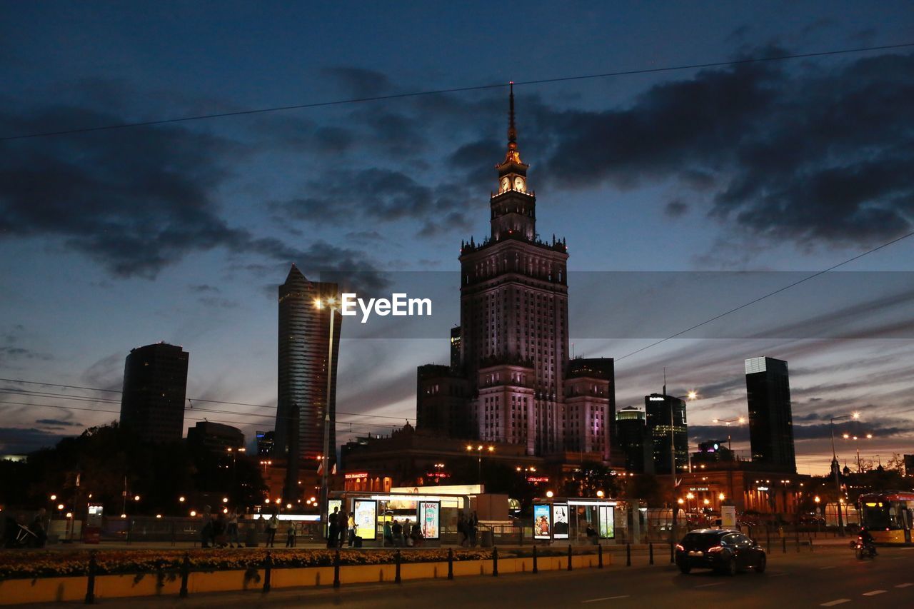 Palace of culture and science by city street against sky at dusk