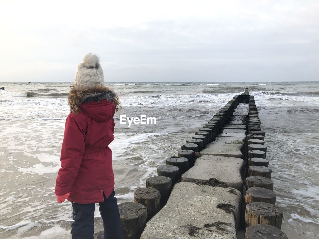 REAR VIEW OF WOMAN LOOKING AT SEA SHORE