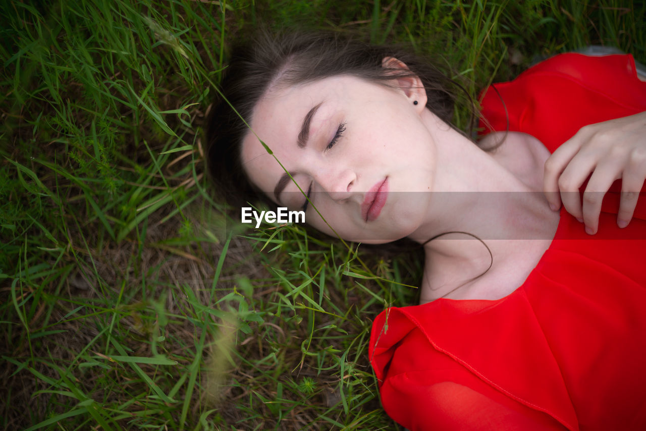 High angle view of young woman sleeping on grassy field